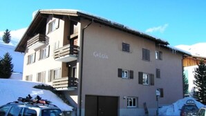 A multi-story building with balconies, a sign reading 'Gelgia,' and a parking area with cars. - Gelgia Sommer-Salis Appartement/Fewo, Bad, WC, 2 Schlafräume by Interhome (Bivio)