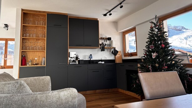 A modern kitchen with dark cabinets, a coffee machine, and a window overlooking a snowy landscape. - Bergnest 4 Appartement/Fewo, Bad, WC, 2 Schlafräume by Interhome (Bivio)