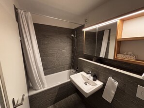 Een moderne badkamer met een bad, een wastafel en een douche.
