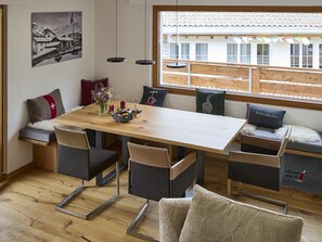 Ein Essbereich mit Holztisch, Stühlen und einer Bank mit Kissen.