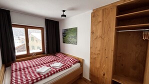 A bedroom with a single bed, a wooden wardrobe, a window with curtains, and a wall-mounted picture. - Bergnest 4 Appartement/Fewo, Bad, WC, 2 Schlafräume by Interhome (Bivio)