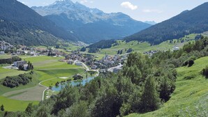 A valley with a small town, surrounded by mountains and greenery.
