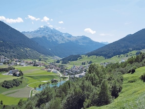 Une vallée abritant une petite ville, entourée de montagnes et de verdure.
