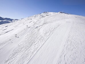 Sneklædt bjergskråning med stolelifte og skiløjper.