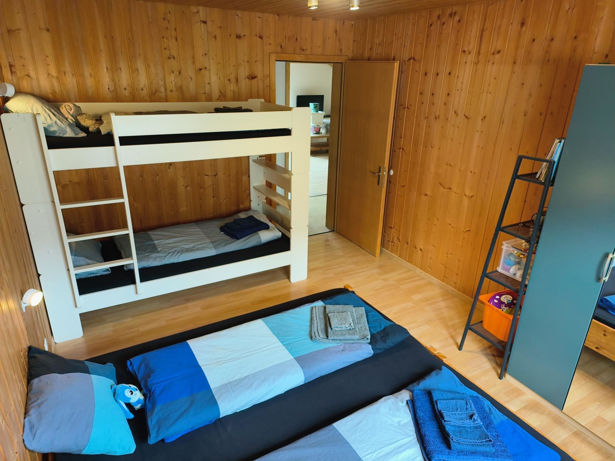 Une chambre avec un lit superposé, un bureau et une étagère.