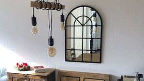 Uma área de refeições com mesa de madeira, bancos e um espelho na parede.