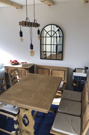 Ein Essbereich mit einem Holztisch, Bänken und einem Spiegel an der Wand.