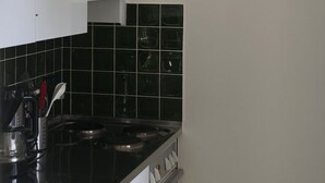 Cozinha com armários brancos, bancada preta e painel de azulejos verdes.