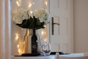 A table with a vase of white flowers, a bottle, and two empty glasses. - Unbeatable Location at March 15 Sq: Quiet, Elegant & Scenic – 333 (Budapest)