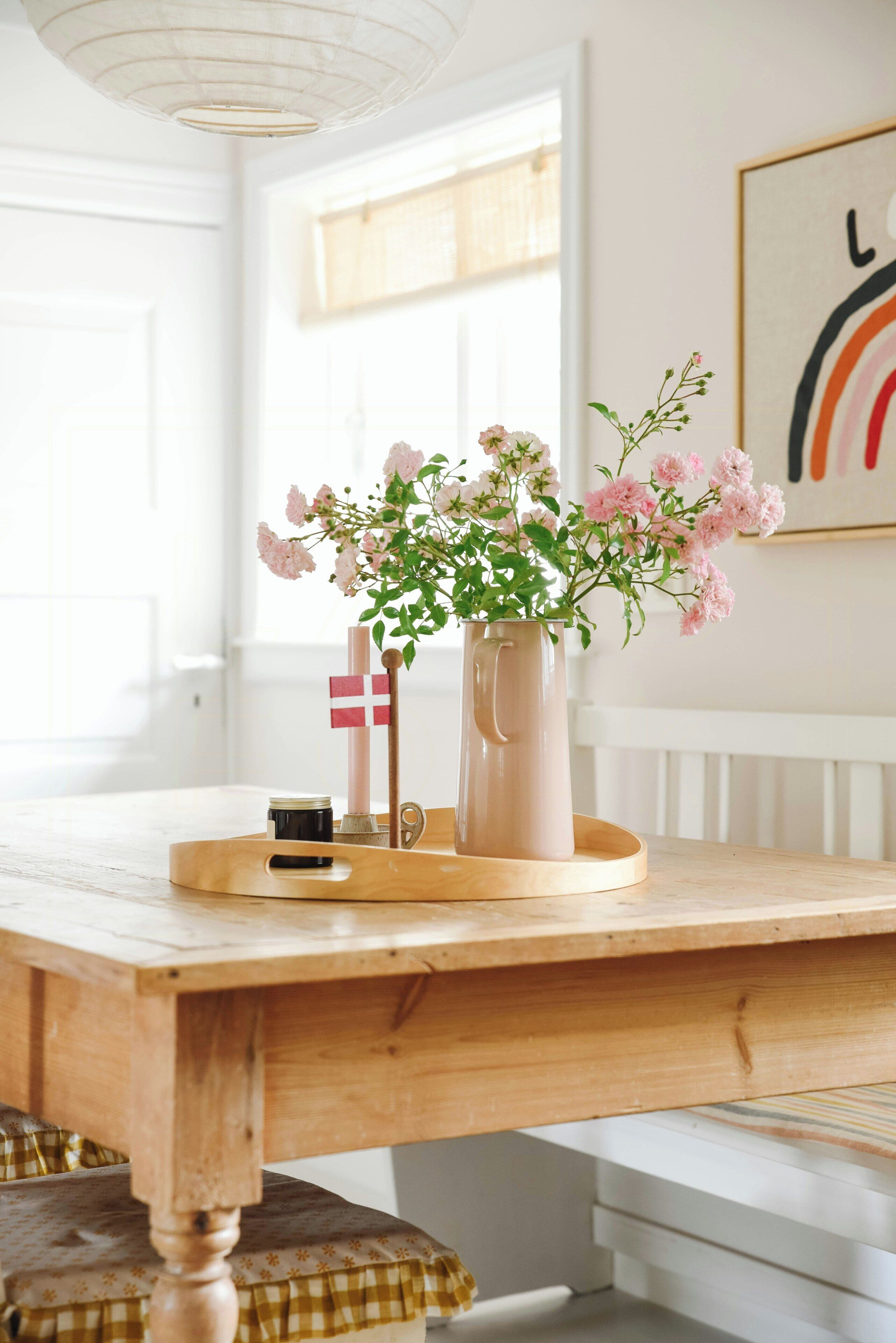 Una mesa de madera con un florero, una vela y una pequeña bandera.