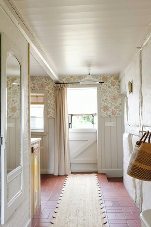 A narrow hallway with a patterned wallpaper, a striped curtain, and a rug leading to a door. - Thatched idyll from the 1800s in Voldtofte (Glamsbjerg)