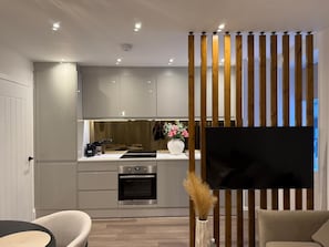 A modern kitchen with built-in appliances, a dining area with a round table, and a living space with a sofa. - Sunniside Sunderland Apartment, walking distance to city centre (Sunderland)