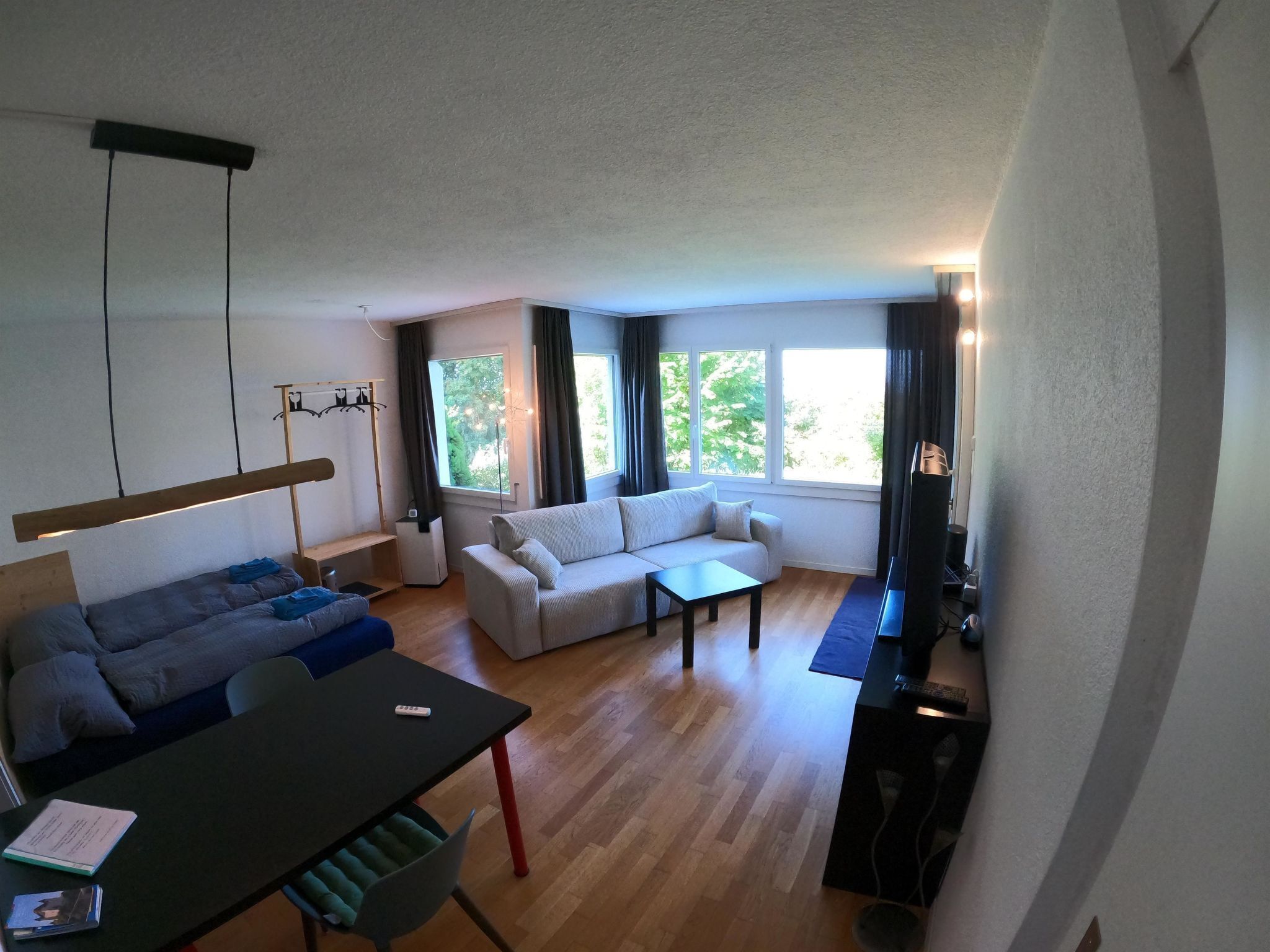 Een moderne woonkamer met een bank, een eettafel en een televisie.