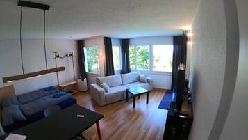 Een moderne woonkamer met een bank, een eettafel en een televisie.