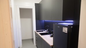 Eine kleine Küche mit einem schwarzen Kühlschrank, einer Spüle und einer Arbeitsplatte.