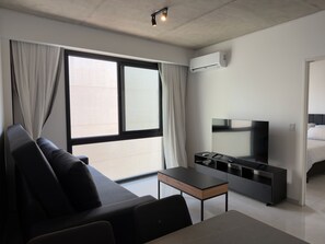 A modern hotel room with a sofa, a TV, a small table, and a large window with curtains. - Luxury 1-Bedroom apt next to University of Palermo (CABA)