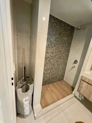 A shower with a tiled mosaic wall, a wooden floor, and a visible showerhead. - Luxury 1-Bedroom apt next to University of Palermo (CABA)