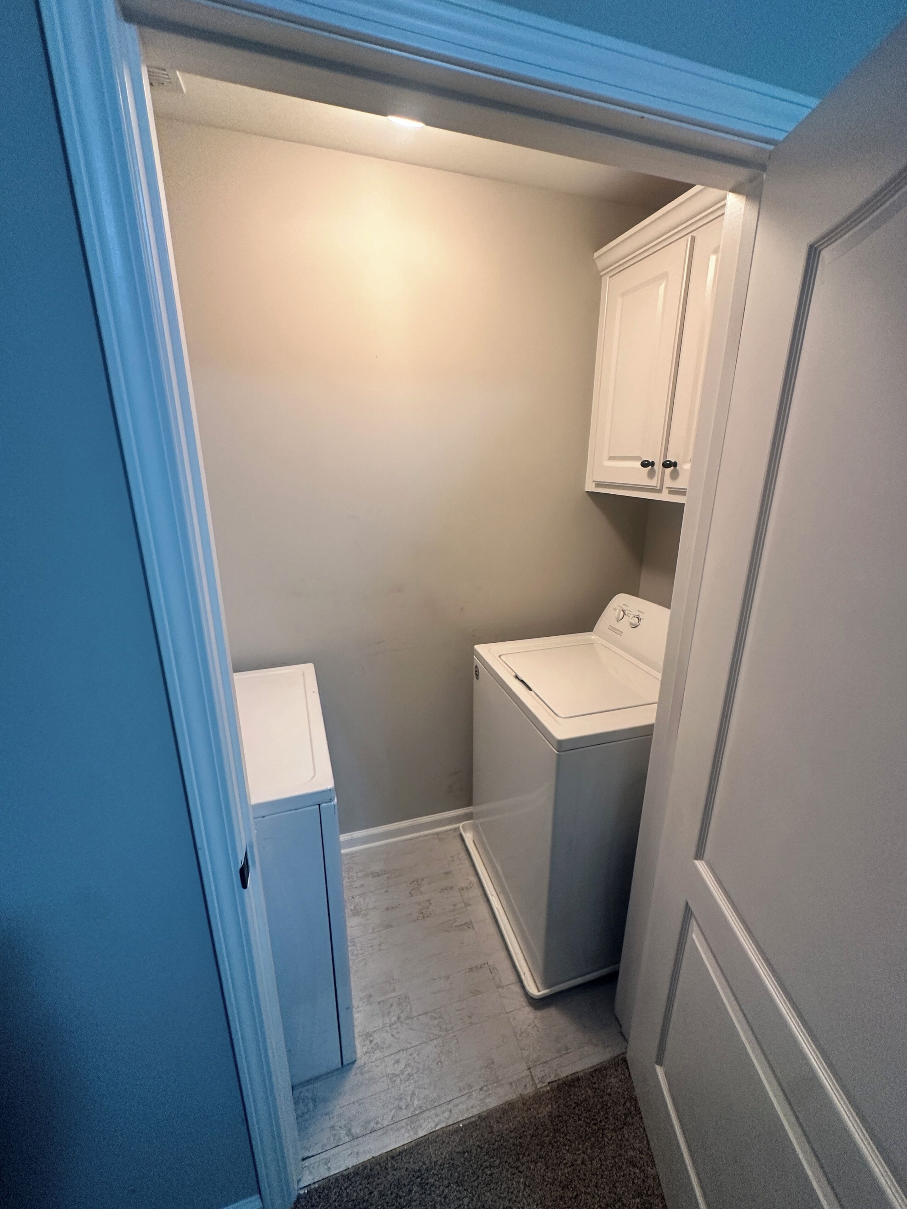 A laundry room with a washing machine and cabinets.