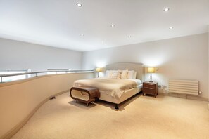 Ein Schlafzimmer mit Bett, Nachttischlampen, einem Nachttisch, einer Heizung und einem Balkon.