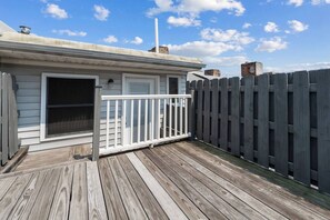 A wooden deck with a white railing, a door, and a fenced area. - Stylish 3-bedroom, 3-bath townhome in one of Baltimore's most walkable neighborhoods steps from Little Italy, Fells Point's cobblestone streets, and the Inner Harbor waterfront (Baltimore)