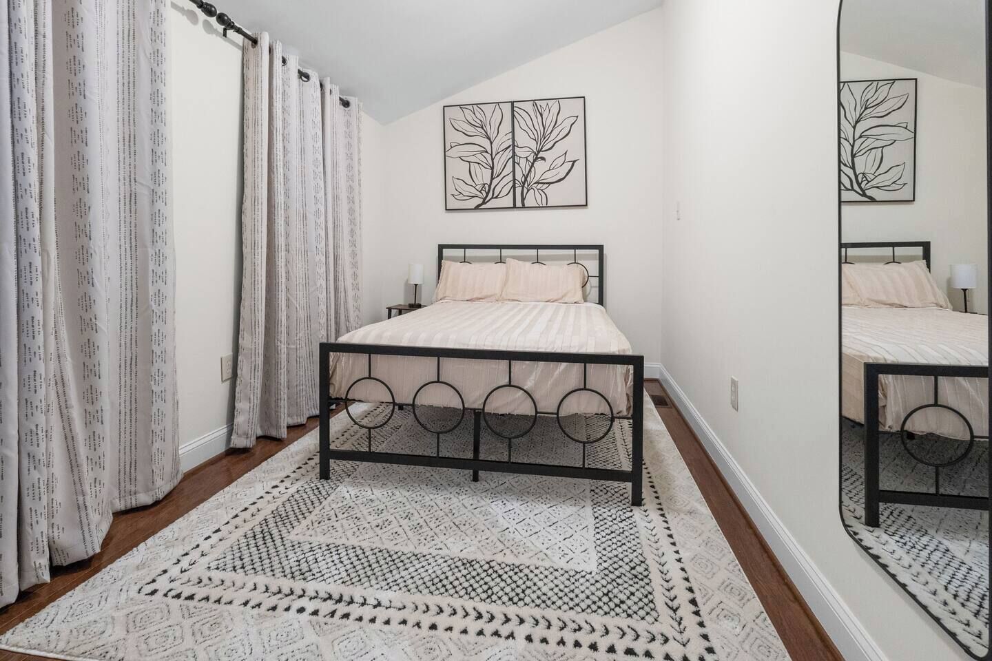 Een slaapkamer met een bed, gordijnen, een vloerkleed en wanddecoratie.