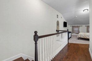 A bedroom with a wooden floor, a bed, a TV, and a window with curtains. - Stylish 3-bedroom, 3-bath townhome in one of Baltimore's most walkable neighborhoods steps from Little Italy, Fells Point's cobblestone streets, and the Inner Harbor waterfront (Baltimore)