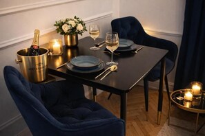 A dining table set with blue plates, a bottle of champagne, glasses, and candles. - The Gem of Downtown: Scenic Boutique Hideaway by the Promenade – 312 (Budapest)