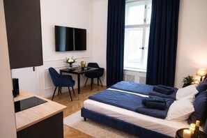 Ein modernes Hotelzimmer mit Bett, Schreibtisch, Sessel und Fernseher.