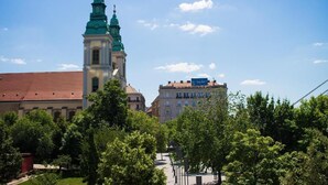 A church with a prominent tower and a building with a sign in the background. - The Gem of Downtown: Scenic Boutique Hideaway by the Promenade – 312 (Budapest)