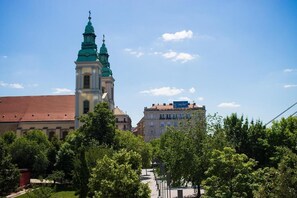 Eine Kirche mit einem markanten Turm und ein Gebäude im Hintergrund, das eine Schilderung trägt.