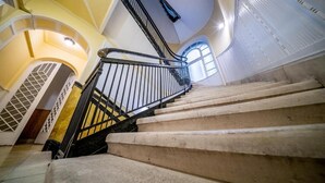 A staircase with a metal railing leading to a landing with a glass door. - The Gem of Downtown: Scenic Boutique Hideaway by the Promenade – 312 (Budapest)