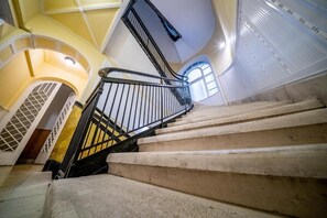 Eine Treppe mit Metallgeländer führt zu einer Zwischenebene mit einer Glastür.