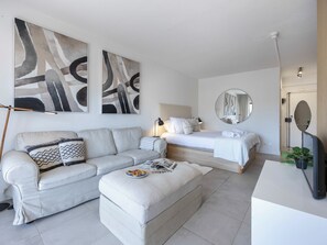 Une chambre moderne avec un lit, un canapé, une table basse et des œuvres d’art abstraites accrochées au mur.