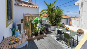 A rooftop patio with a table set for dining, a grill, and various potted plants. - Casa Abraço - River View Terrace in Ferragudo (Ferragudo)