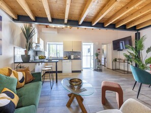 A modern living space with a kitchen, dining area, and a TV mounted on the wall. - Casa Abraço - River View Terrace in Ferragudo (Ferragudo)