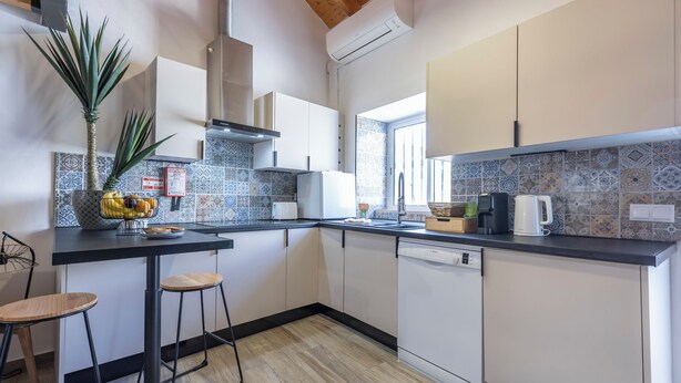 A modern kitchen with a wooden ceiling, a dishwasher, a coffee maker, and a fruit bowl on the counter. - Casa Abraço - River View Terrace in Ferragudo (Ferragudo)