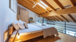 A bedroom with a wooden ceiling, a bed with pillows, a bedside lamp, and a view through a window. - Casa Abraço - River View Terrace in Ferragudo (Ferragudo)