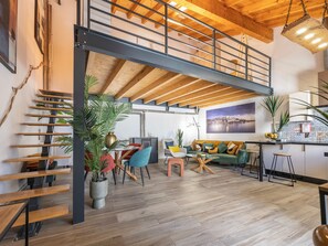 A spacious loft with a mezzanine, wooden flooring, a dining area, and a view of a cityscape. - Casa Abraço - River View Terrace in Ferragudo (Ferragudo)
