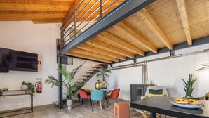 A modern interior with a wooden ceiling, a staircase, a flat-screen TV, and a dining area with a table and chairs. - Casa Abraço - River View Terrace in Ferragudo (Ferragudo)