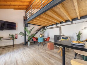 Ein modernes Interieur mit Holzboden, einer Treppe, einem Flachbildfernseher und einem Essbereich mit Tisch und Stühlen.