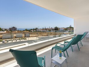 A balcony with a view of the sea, a parking area, and green chairs. - Lagos Odyssey - Sea Views and Dona Ana Bay (Lagos)