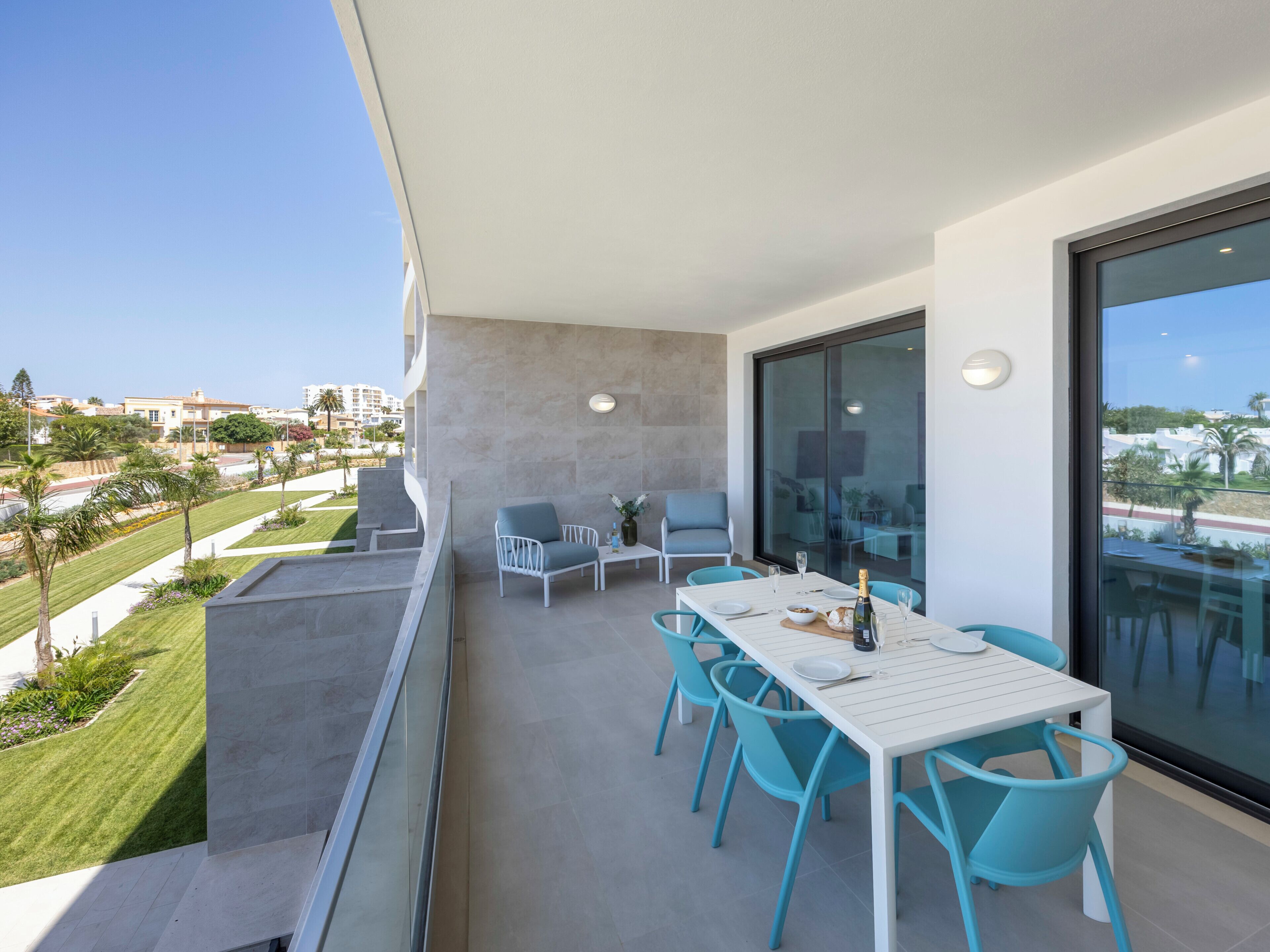 A balcony with a table and chairs, a view of the city, and a clear sky.
