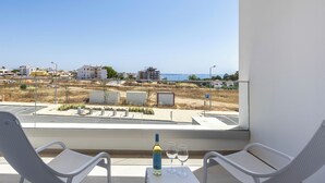 A balcony with two white chairs, a small table, and a bottle of wine and two glasses. - Lagos Odyssey - Sea Views and Dona Ana Bay (Lagos)