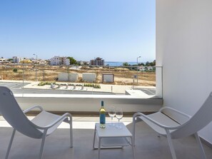 A balcony with two white chairs, a small table, and a bottle of wine and two glasses. - Lagos Odyssey - Sea Views and Dona Ana Bay (Lagos)