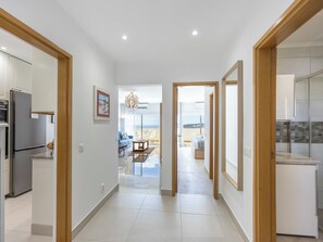 Eine moderne Küche mit Kühlschrank, ein Essbereich mit Tisch und Stühlen sowie ein Flur, der auf einen Balkon mit Aussicht führt.