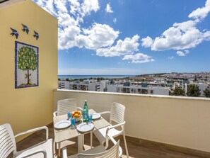 A balcony with a table set for two, overlooking a coastal cityscape. - Casa Benção - Sea View and Pool in Lagos (Lagos)