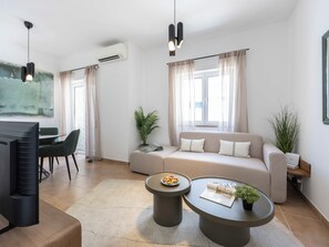 A modern living room with a sofa, a coffee table, a dining area with chairs, and a television. - Casa Horizonte - Old Town Lagos (Lagos)