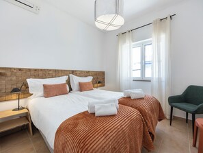 A hotel room with a bed, bedside tables, a lamp, a chair, and a window with curtains. - Casa Horizonte - Old Town Lagos (Lagos)