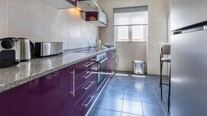 A modern kitchen with a granite countertop, stainless steel appliances, and a window providing natural light. - Casa Horizonte - Old Town Lagos (Lagos)