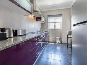 Uma cozinha moderna com bancada de granito, eletrodomésticos de aço inoxidável e uma janela que proporciona iluminação natural.
